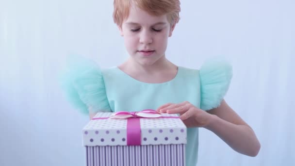 Nastoletnia dziewczyna w pięknej sukni wieczorowej. Dziecko otwiera pudełko z prezentem. Emocje zaskoczenia i szczęścia z niespodzianki w pudełku — Wideo stockowe