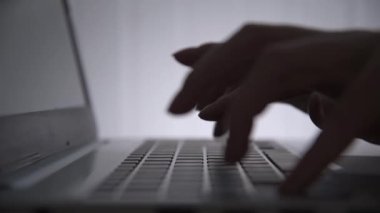 Karanlıkta hackerların elleri klavyede çalışır. Siber suçlar. Bir kişi geceleri bir dizüstü bilgisayarda çalışır. Gizem ve sır kavramı. Seçici odaklanma, yumuşak odaklanma