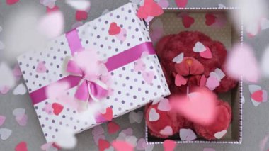 Sevgililer Günü konsepti. Zarif ve güzel bir kutuda bir hediye. Oyuncak ayı. Konfeti kalpler yukardan düşer. Şirin ve romantik bir resim.