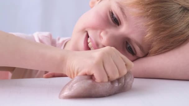 A criança gosta de brincar com lodo. Brinquedo anti-stress. Emoções positivas, sorriso. Cara de perto, retrato. — Vídeo de Stock