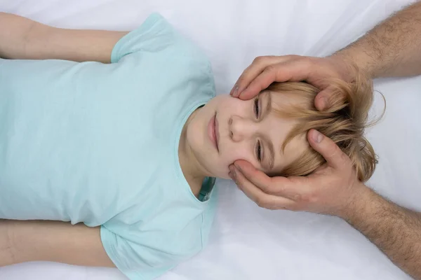 L'ostéopathe travaille avec la tête des enfants. Une adolescente s'allonge sur un canapé. Le médecin palpe doucement la tête — Photo