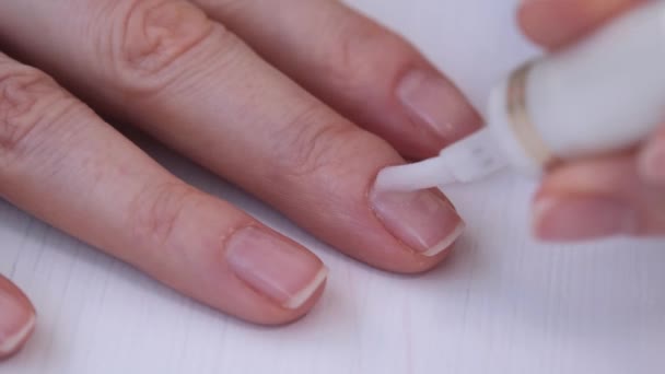 Las manos de las mujeres cierran. La niña se cubre las uñas con un barniz médico transparente. Manicura natural. Cuidado de las uñas. Fortalecimiento de las uñas con la ayuda de agentes terapéuticos — Vídeos de Stock