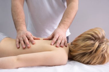 Osteopat omurgayla çalışıyor. Genç bir çocuk bir doktorun önündeki kanepede yatıyor. Bir kayropraktik uzmanı omurgayı inceler. Duruş düzeltmesi