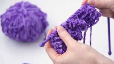 Kadın bağladığı şeyi inceliyor. Mor iplik rengi. Moda eğilimi rengi.