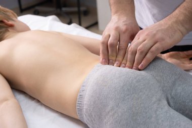 Osteopat kuyruk sokumu bölgesinde çalışıyor. Kayropraktik uzmanı sırt ve kuyruk sokumuyla çalışır.
