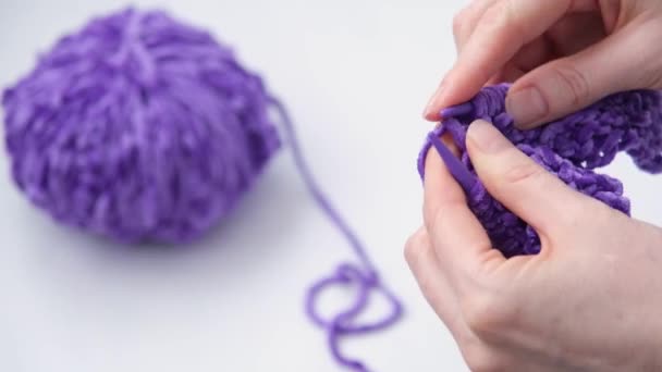 O processo de tricô. Close-up de mãos de mulheres. Tricotar. Foco seletivo. No fundo é uma bola de fio. Moda cor de fio roxo na moda. — Vídeo de Stock
