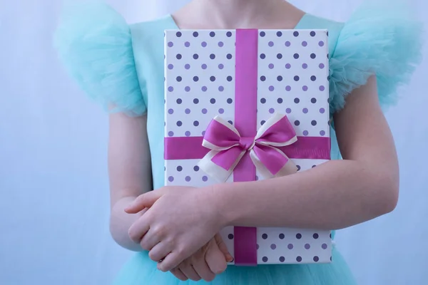 Las manos de los niños están cerca. Un niño con un vestido de noche sostiene una caja de regalos. El concepto de un regalo, una sorpresa. Hermosa caja — Foto de Stock