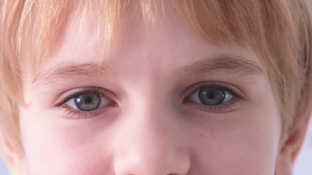Τα μάτια του παιδιού είναι κοντά. Ένα γαλανομάτικο παιδί κοιτάζει στην κάμερα. Μαθητής ή μαθήτρια με κόκκινα μαλλιά. — Αρχείο Βίντεο