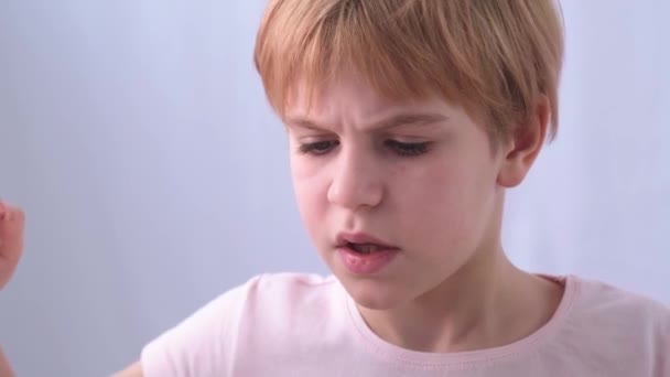 Primer plano de la cara de los artistas infantiles. Un hombre pequeño y talentoso pinta diligentemente un cuadro con un pincel. El rostro expresa emociones. Concentración y seriedad. Hermosa pelirroja con un corte de pelo corto — Vídeo de stock