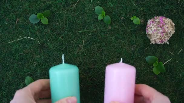 Dámské ruce rozkládají voskové svíčky na přirozeném pozadí. Zelené pozadí, tráva, mech a rostliny. Koncept přírodního produktu. Koncept péče o životní prostředí — Stock video