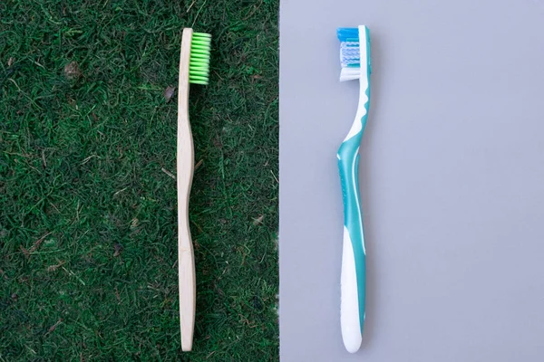 Deux brosses à dents sur deux fonds différents. Brosse en plastique sur fond plastique. Brosse à dents écologique en bois sur fond vert naturel. Mousse et herbe. Concept. comparaison. Voilà. — Photo