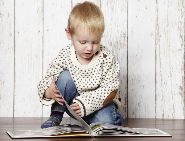 Petit garçon lisant un livre Image En Vente