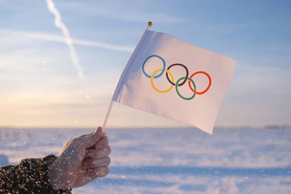雪と木を背景に 手に小さなオリンピックフラグは フルート冬のオリンピック2022のコンセプト — ストック写真