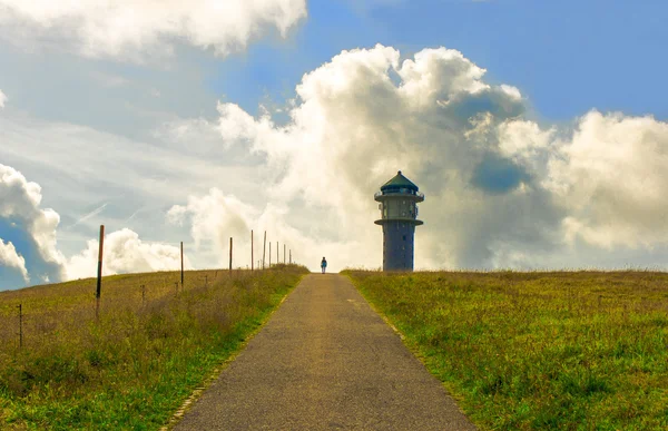 Weg naar een toren in het groene gras en wolken op de berg — Stockfoto