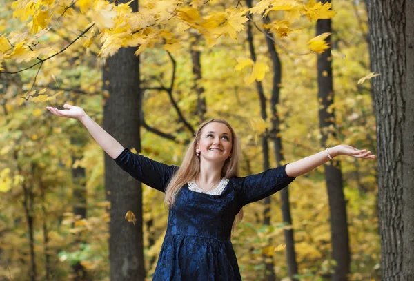 Young woman with falling autumn leaves — Stock Photo, Image