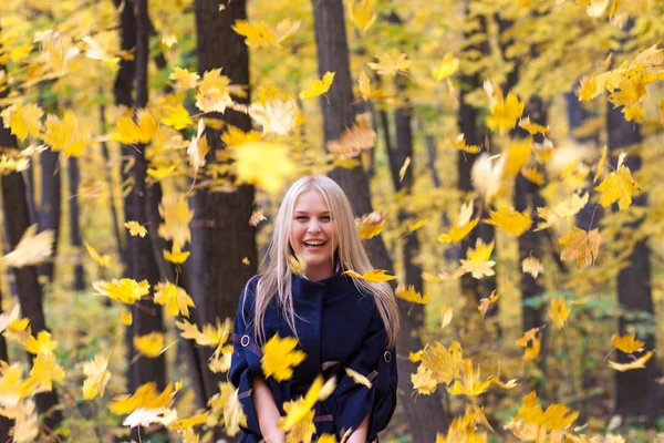 Young woman with falling autumn leaves — Stock Photo, Image