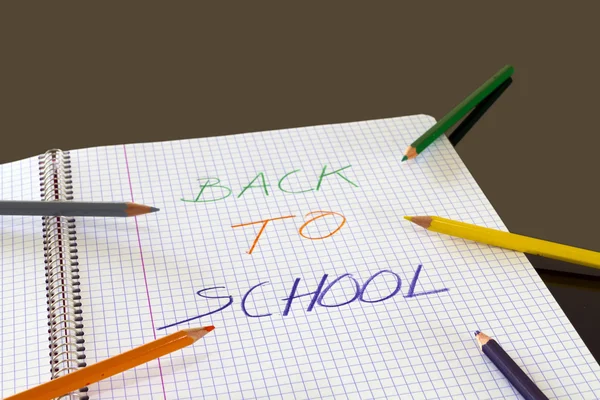 Volver a la escuela escrito en color en el libro, con lápices de colores alrededor — Foto de Stock