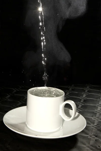 Verser de l'eau chaude et torride dans une tasse blanche — Photo