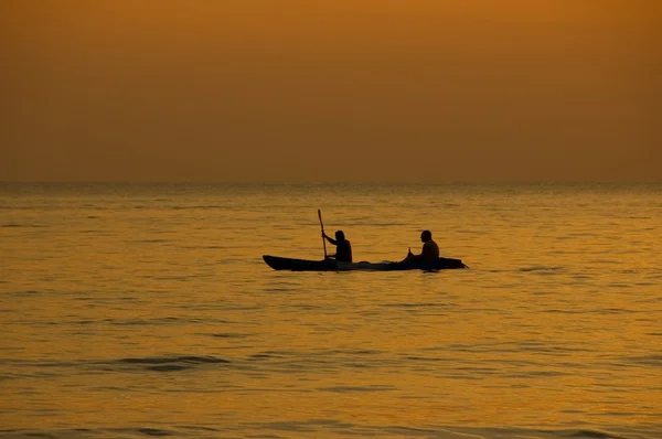 Двое мужчин в лодке на закате — стоковое фото