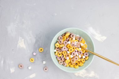 Kaşıklı bir kasede çok renkli meyve halkaları.