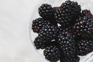 Gri arka planda desenli cam kasede taze böğürtlen