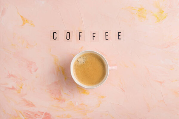 Cup of espresso coffee and text COFFEE on pink background