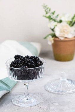 Gri arka planda desenli cam kasede taze böğürtlen