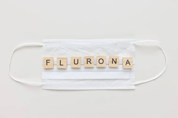 Word FLURONA on mask, white background. COVID and flu double infection concept — Stock Fotó