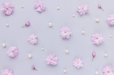 Fresh cherry blossom sakura flowers and pearls on pastel pink background. Abstract floral pattern