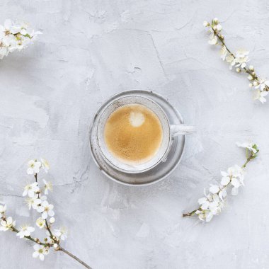 Bir fincan siyah espresso kahve ve gri arka planda beyaz kiraz çiçekleri, kopyalama alanı.