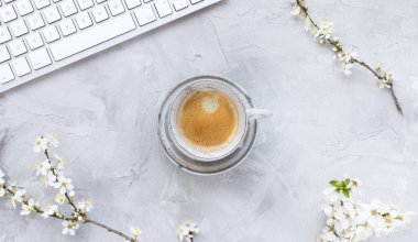 Beyaz kiraz çiçekleri ve sabah espresso kahvesiyle bahar gri arka planda bilgisayar klavyesi, boşluğu kopyala