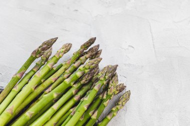 Gri arka planda taze çiğ yeşil kuşkonmaz mızrakları, kopyalama alanı
