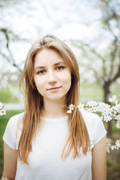 桜の木の下に長い髪の若い女性 白いTシャツのモックアップ ライフスタイル女子学生の肖像画 — ストック写真