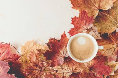 Cup of espresso with crema and autumn red maple leaves on white background. Fall season mood, flat lay. Top view, copy space