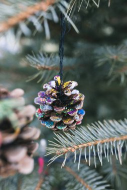 Handmade natural painted pine cone decoration on Christmas tree. Diy ideas for children. Environment, reuse, recycle, upcycling and zero waste concept. Selective focus