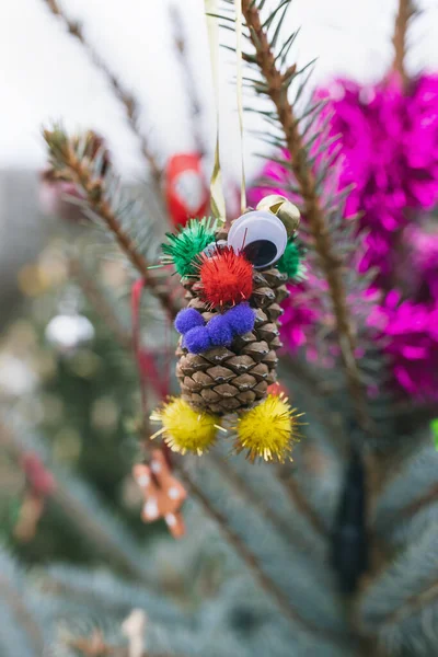 Pine cone, fluffy felt balls and googly eyes for crafts on Christmas tree. Diy decoration ideas for children. Environment, recycle, upcycling and zero waste concept. Selective focus, outdoor