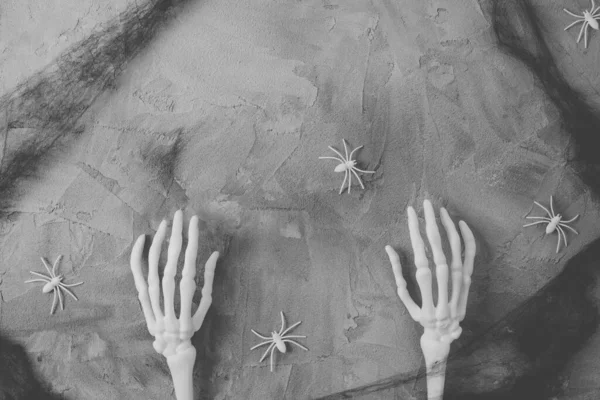 Mystery Halloween flat lay with monster skeleton hands, black spider cob web and white spiders, dark gray background. Happy Halloween banner mock-up. Top view, copy space