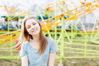 Happy young Gen Z woman in an amusement park, smiling. Copy space. Summer time