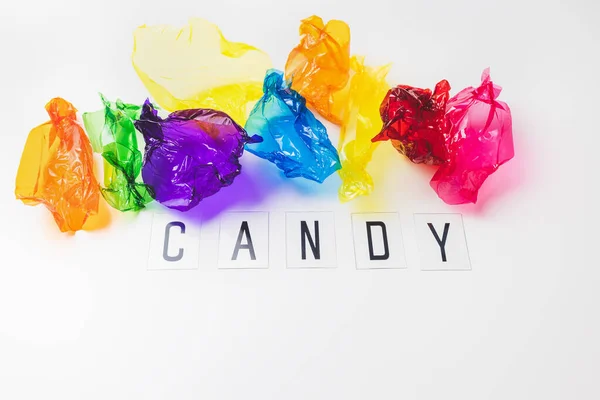 Colorful candy wrappers and text CANDY on white. Sugar sweets concept. Abstract colorful background with copy space