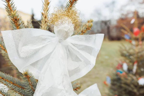 Handmade angel decoration of plastic foil and wire on Christmas tree outdoor. Diy creative ideas for children. Environment, recycle and zero waste concept. Selective focus, copy space