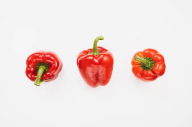 Beyaz arka planda üç taze olgun kırmızı dolma biber. Sağlıklı vejetaryen yemekleri ve yemek pişirme konsepti. Üst görünüm, alanı kopyala