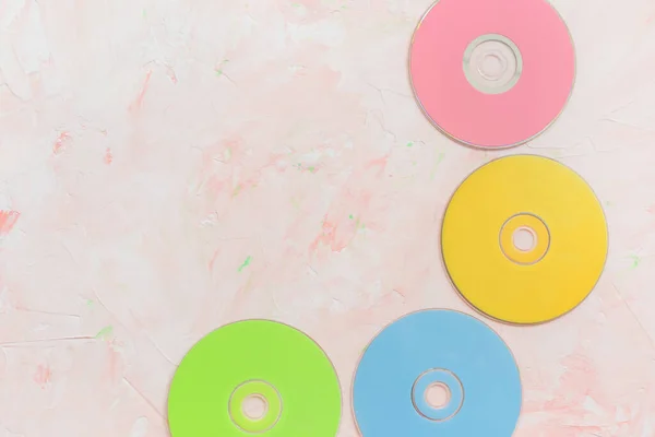 Colorful CD or DVD discs on pink. Retro minimalist background, 80s trend, copy space