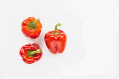 Beyaz arka planda üç taze olgun kırmızı dolma biber. Sağlıklı vejetaryen yemekleri ve yemek pişirme konsepti. Üst görünüm, alanı kopyala