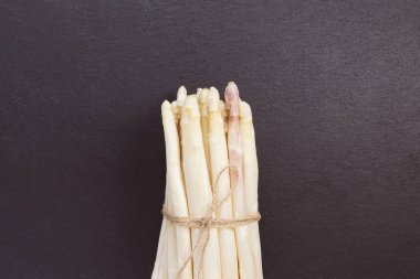 Siyah arka planda taze çiğ beyaz kuşkonmaz mızrakları. Sağlıklı sebzeler, vejetaryen yemekleri ve yemek pişirme konsepti için malzemeler. Yaklaş, boşluğu kopyala.