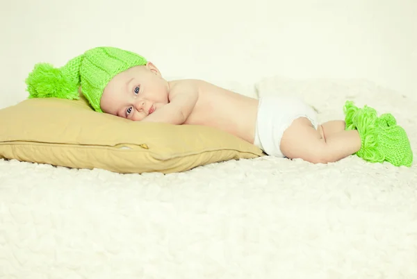 Sad baby in a green cap and slippers — Stock Photo, Image