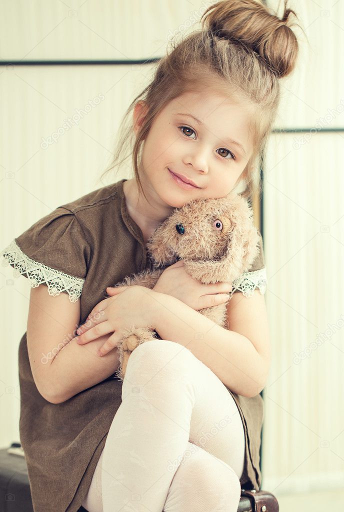 The little girl holds a toy.