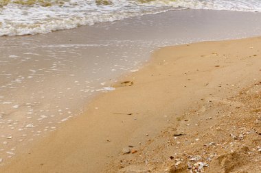 Sahilin ıslak kumu üzerindeki ayak izleri suyla yıkanır..