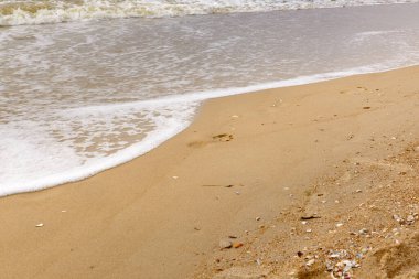 Sahilin ıslak kumu üzerindeki ayak izleri suyla yıkanır..