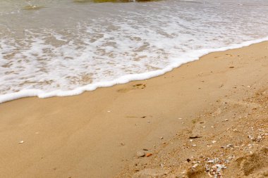 Sahilin ıslak kumu üzerindeki ayak izleri suyla yıkanır..