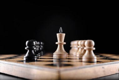 Tahta bir tahtanın üzerinde çeşitli ışıklarla tahta satranç taşları..